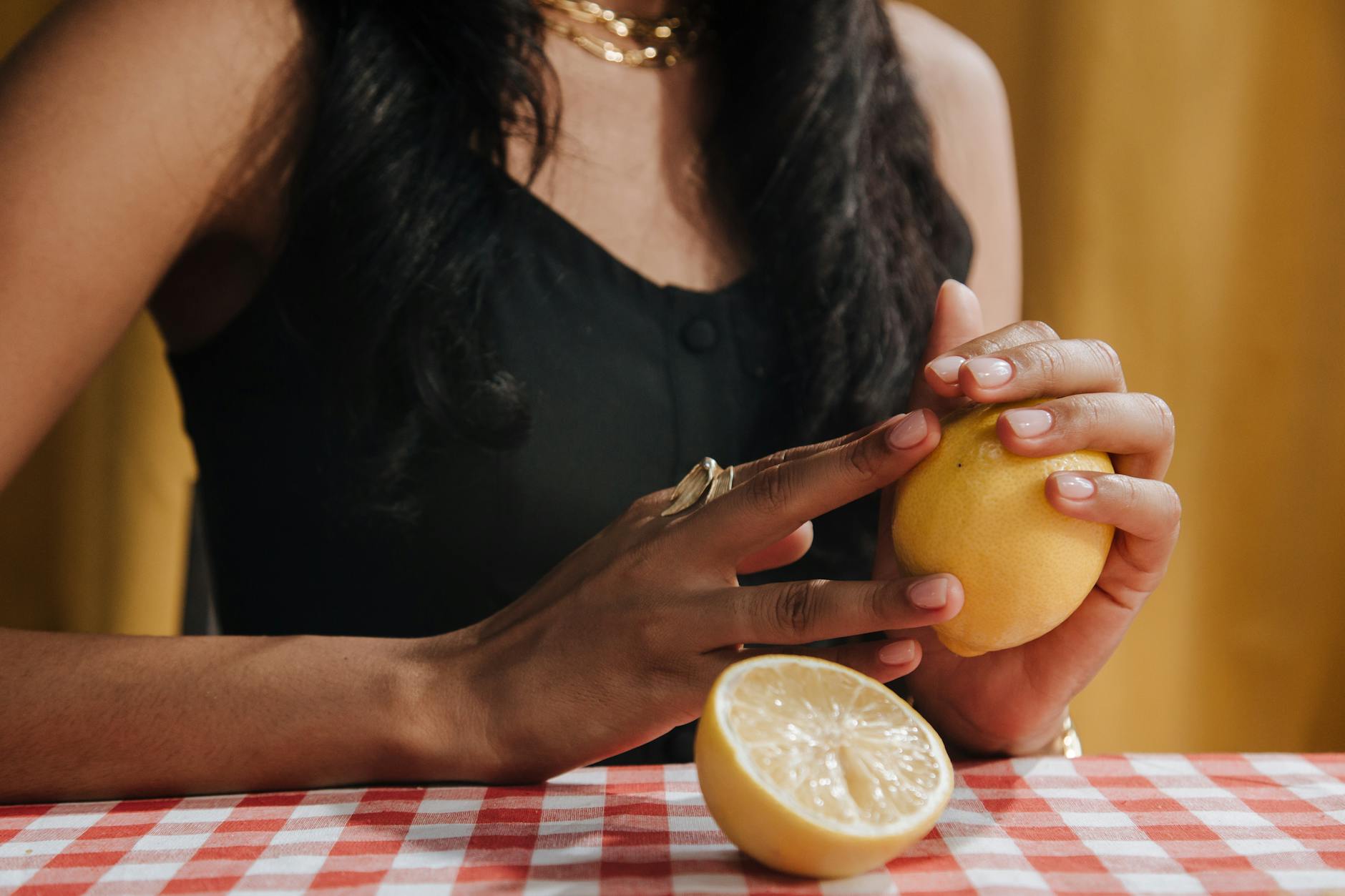 Eine Hand hält einen orangen Vibrator vor neutralem lila Hintergrund