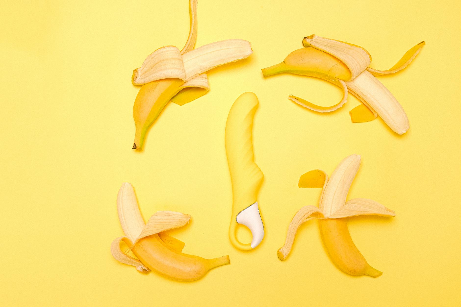 Gelber Silikon-Saugvibrator auf gelbem Hintergrund, umgeben von frischen Zitronenscheiben