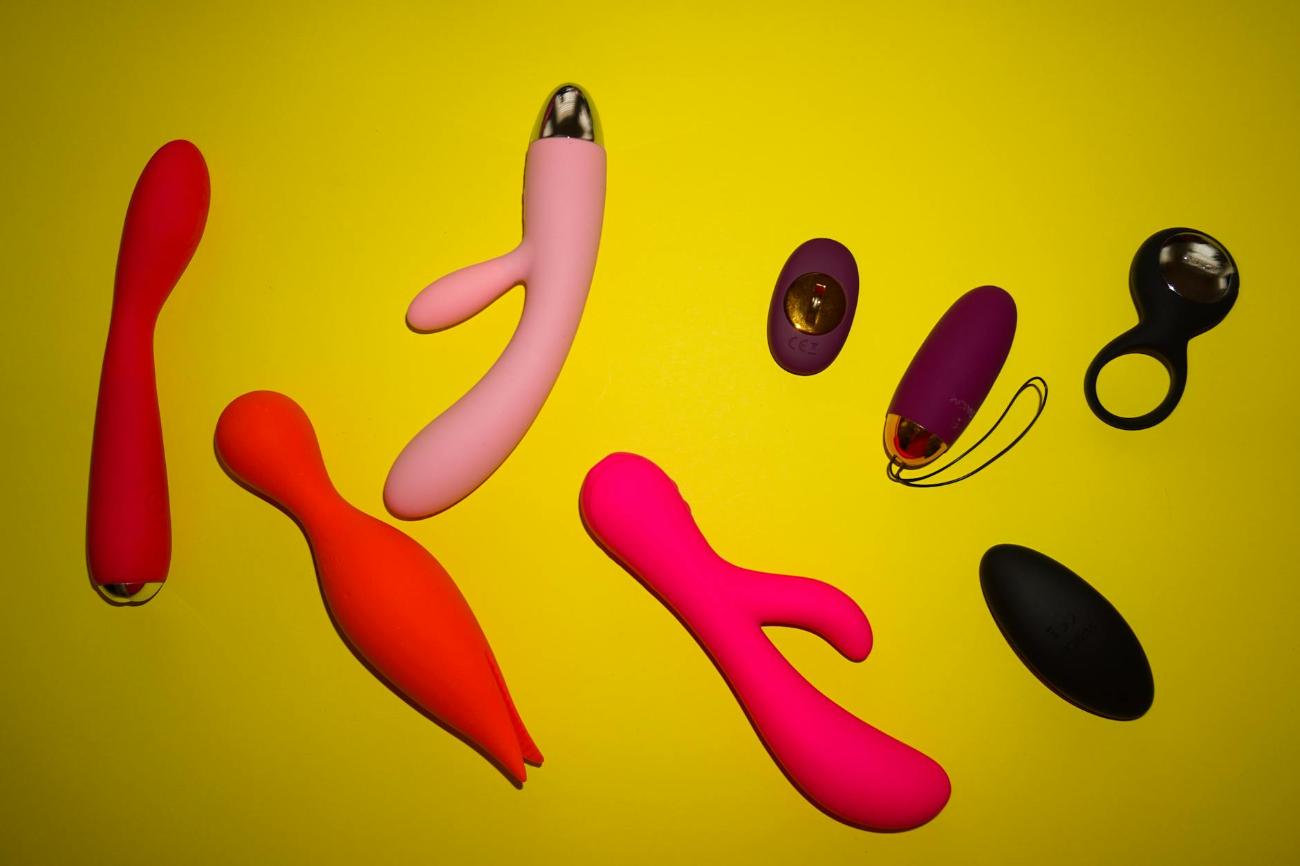 A blue silicone clitoral vibrator held in hand against a solid purple background