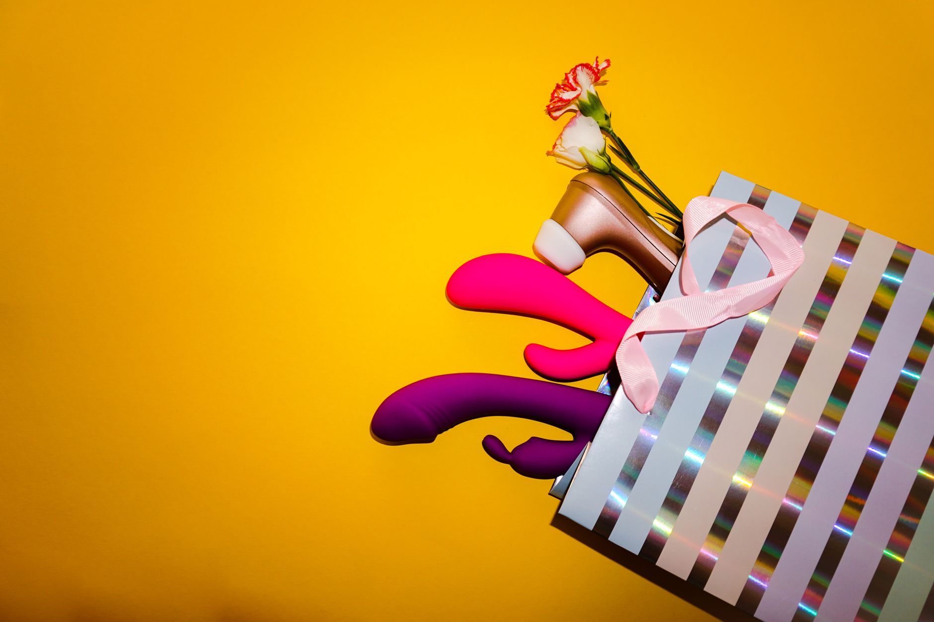 Colorful vibrators and adult toys on a bright yellow background, representing diverse pleasure options.