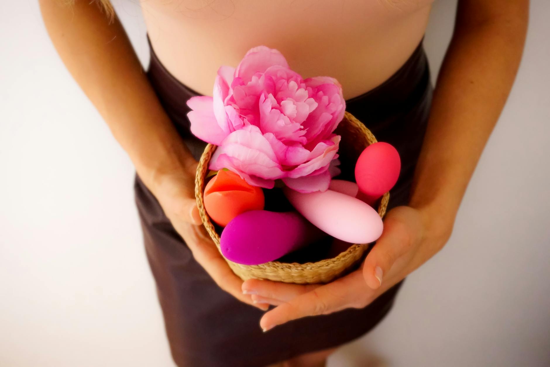 Eine Hand hält einen orangefarbenen Vibrator vor minimalistischem lila Hintergrund, moderne Sinnlichkeit und Selbstbestimmung.
